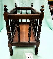 Side view showing the detailed turned wooden spindles and the solid wood base shelf of the magazine rack.