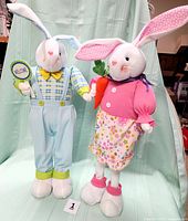 Front view of both the freestanding boy and girl bunny dolls showcasing detailed outfits and accessories.