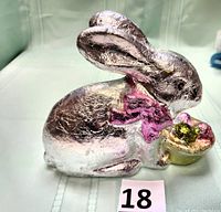 Faux silver foil-wrapped rabbit figurine holding a basket of eggs, side view showing pink bow on neck and gold basket detail.