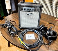 TranZamp G8 guitar amplifier with two instrument cables and Sony MDR-V600 headphones arranged on a wooden table.