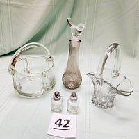 Photo showing all items: clear glass basket, flower vase/basket, smoked glass perfume decanter with bird stopper, and mini salt and pepper shakers.