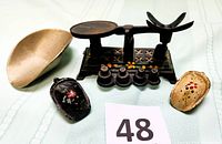 Photo showing vintage cast iron balance scale with four counterweights and removable brass-colored basket bin along with two mini salt and pepper scoops with floral designs.