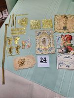 Photo showing laid out vintage valentines and multiple gold German foil decorative strips including hearts, cherubs, and borders.