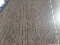 Close-up image showing the warm greyish-brown colored engineered oak hardwood plank with visible wood grain texture.