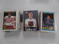 Stacks of hockey cards showing players Joe Sakic, Brett Hull, and Sergei Federov, featuring team logos such as Detroit Red Wings and Quebec Nordiques, with cards individually sleeved.