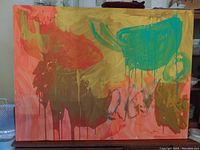 Front view of large abstract canvas painting with colorful dripping paint in warm tones.