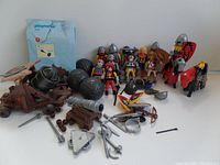 Display of all Playmobil knights, horses, weapons, shields, catapults, and accessories on a flat surface