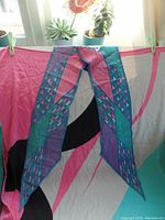 Photo of Monique Martin scarf or belt with blue, purple, and pink geometric pattern hung in front of a window