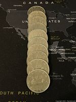 Ten Canadian dollars arranged face down showing the voyageur and canoe design with date 1968 on the nearest coin.