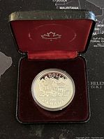 Front view of silver proof dollar coin in red velvet presentation case showing maple leaf on lining.