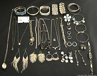 Full view of assortment including bracelets, necklaces, rings, earrings, and watch all displayed on black surface