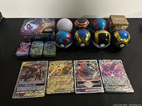 Wide view of all items including 9 different Poké Balls, 3 Pokémon collectible tins, and 4 Pokémon cards laid out on a black surface.