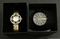 Two watches in individual black boxes, one black Armani Exchange watch and one decorative gold-tone watch with star-shaped frame