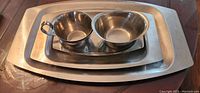 Photo showing nested 3 metal trays with a gravy boat and 2 bowls on the smallest tray.