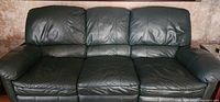 Full front view of the large green leather sofa couch showing three seat cushions, three back cushions, and padded armrests.