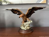 Front view of detailed eagle sculpture with spread wings on wooden base.