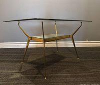 Front three-quarter view showing overall table structure, brass frame and glass top