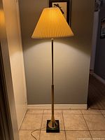 Full view of the lamp assembled with lamp shade illuminated showing overall design and height.