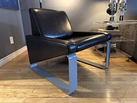 Three-quarter left view showing vinyl upholstery and metal sled base