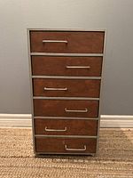 Front view of vintage cabinet showing 6 wooden drawers with metal handles within metal frame, standing on casters.