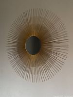 Front view of sunburst mirror showing the round mirror surround of brass rods radiating outward.