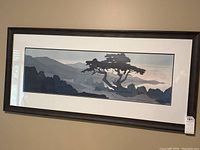 Full view of the framed landscape artwork showing tree silhouettes against mountain ranges.