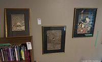Three framed prints hanging on wall over bookshelf