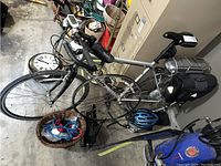 Full view of silver Marin hybrid bicycle with mounted BionX battery pack on rear rack, flat handlebars and blue helmet on floor.