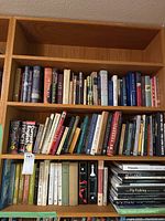 Books arranged on a wooden bookshelf showing a wide variety of titles and genres including language learning and literature.