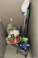 Overview of cleaning supplies including broom, mops, brushes, cloths, and bucket with cleaning products.