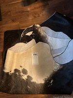 Close up of rug folded showing black, white and brown/gray pattern with tag showing approximate size 73 x 78