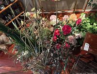 Tall faux flower arrangement with green seedpods and assorted greenery clustered together