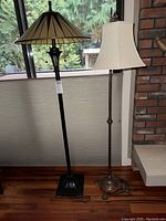 Full view showing both floor lamps side by side in front of a window