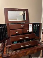 Open dark brown wooden jewelry box with mirror and drawers