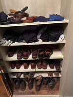 Shelf with multiple pairs of men's leather shoes in sizes 11 and 12, and folded men's sweaters in dark tones.