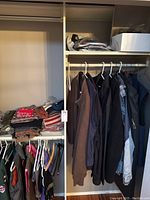 Wide view of closet with folded scarves, hats, mittens on shelves and jackets/vests hanging on rods