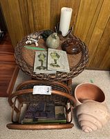 Rattan round side table with woven top, ceramic turtle and bird figurines, candle, ceramic handles, magazine rack with books and large terracotta conch shell planter.