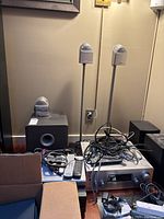 Stereo equipment with speakers, amplifier, remote controls and cables shown on floor and stands.