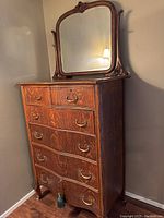 Front view of tall boy dresser and attached mirror showing six-drawer configuration and medium brown finish