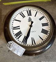 Front view of one side of the two faced clock showing Roman numerals, insignia, and London lettering.