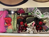 Drawer contents showing various perfume bottles, fabric pouches, pink hard case, hairbrush, and small accessories
