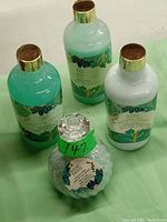 Photo of the four Bonjour Paris bathroom products grouped together: shower gel, body lotion, bubble bath, and a white textured jar, all with labels featuring green and gold leaf patterns.