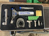 Metal case open showing Dremel Versa Flame torch and accessories in foam cutouts.