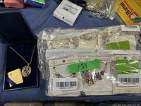 Blue box with gold-toned necklace pendant swirl design and several packs of costume jewelry earrings in plastic packaging