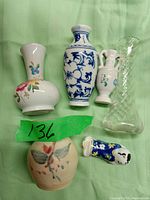 Lot of five small decorative vases in different styles and materials, shown on green background, with tag 136
