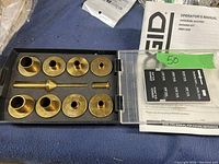 Photo of RIDGID Universal Router Bushing Kit RDK1032 with brass bushings, centering pin, and operator's manual in the case.