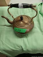 Photo of a vintage brass tea kettle showing the rounded body, curved spout, wooden handle with brass supports, and lid with wooden knob.