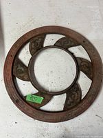 Top view of a vintage cast iron stove pipe grill showing ornate five curved fan blades and outer rim inscriptions