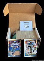 Open box containing stacks of 1992 Wild Card Football trading cards showing some of the front cards including Barry Sanders and Emmitt Smith.