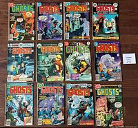 Top view of 12 DC Comics Ghosts issues spread on a wooden floor, showing covers with colorful supernatural scenes and titles.